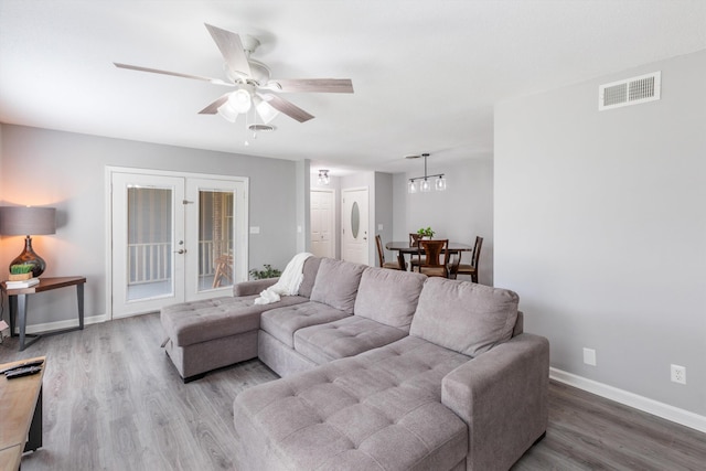 living area with wood finished floors, a ceiling fan, visible vents, baseboards, and french doors