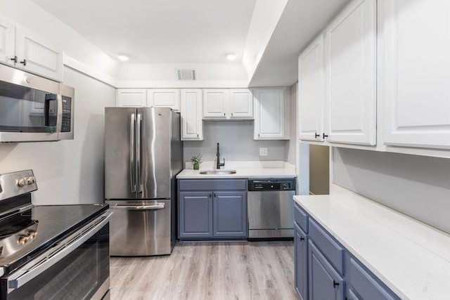 kitchen with blue cabinetry, visible vents, appliances with stainless steel finishes, and a sink