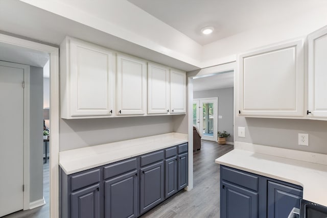 kitchen featuring light countertops, light wood finished floors, blue cabinets, and white cabinets