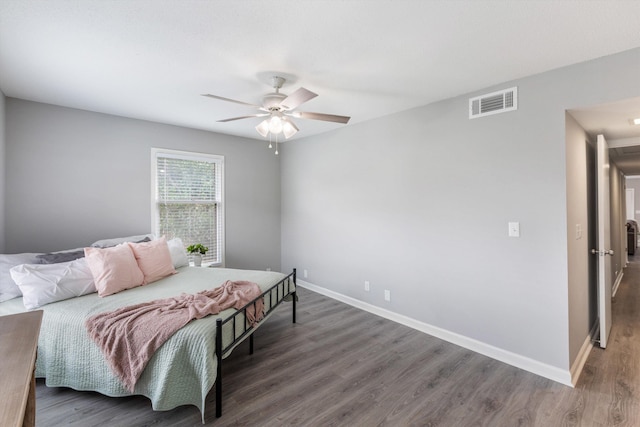 bedroom featuring a ceiling fan, wood finished floors, visible vents, and baseboards