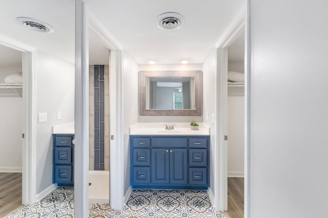 bathroom with a walk in closet, visible vents, and vanity