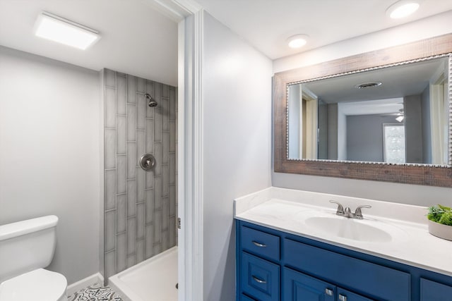 full bath with visible vents, vanity, a tile shower, and toilet