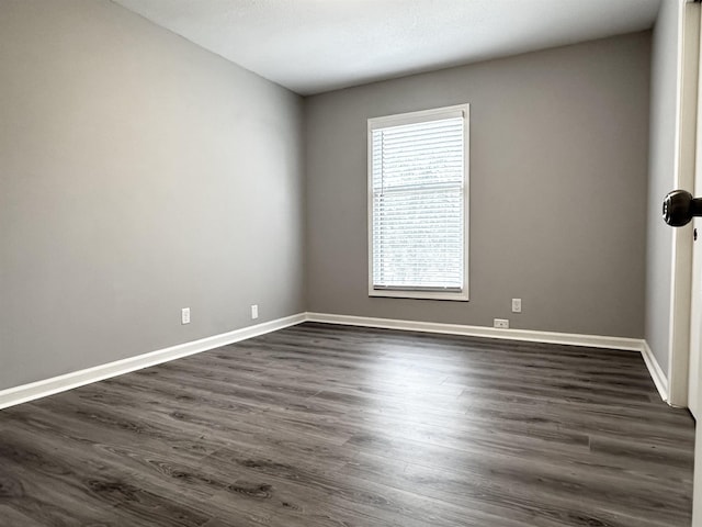 empty room with baseboards and dark wood-type flooring