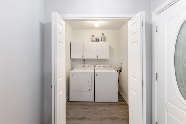 clothes washing area featuring washing machine and dryer, cabinet space, and light wood-style flooring