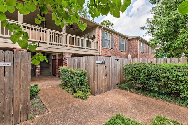 view of side of home with ceiling fan, fence, and brick siding