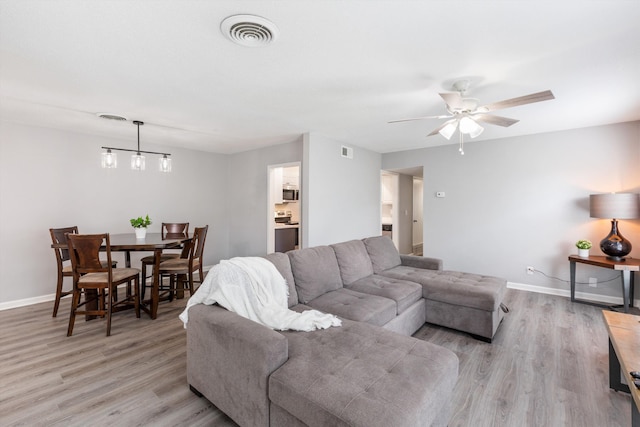 living area featuring baseboards, visible vents, and light wood-style floors