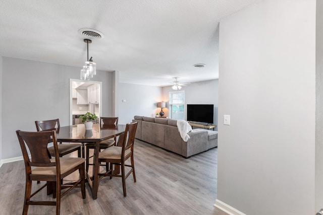 dining area featuring light wood-style floors, baseboards, and visible vents