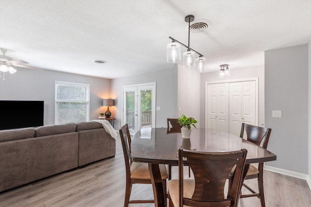 dining space featuring light wood finished floors, a ceiling fan, visible vents, and baseboards