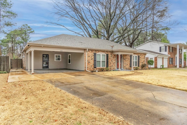 view of front of house featuring brick siding, a shingled roof, fence, an attached carport, and driveway