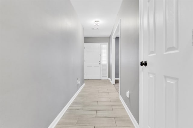 corridor featuring baseboards and wood finish floors