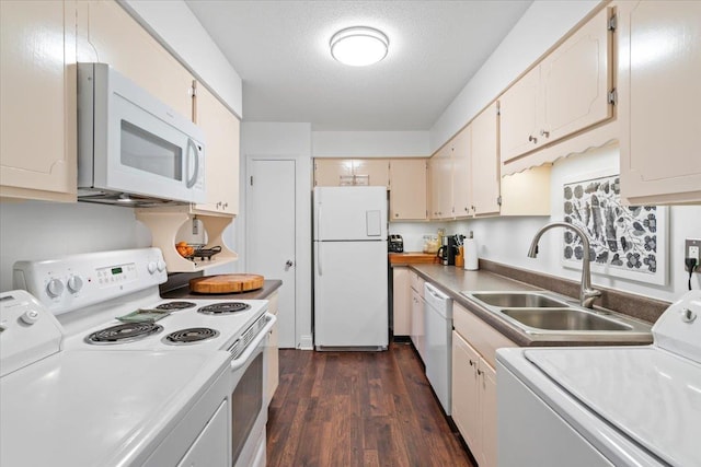 kitchen featuring white appliances, dark wood finished floors, light countertops, washer and dryer, and a sink