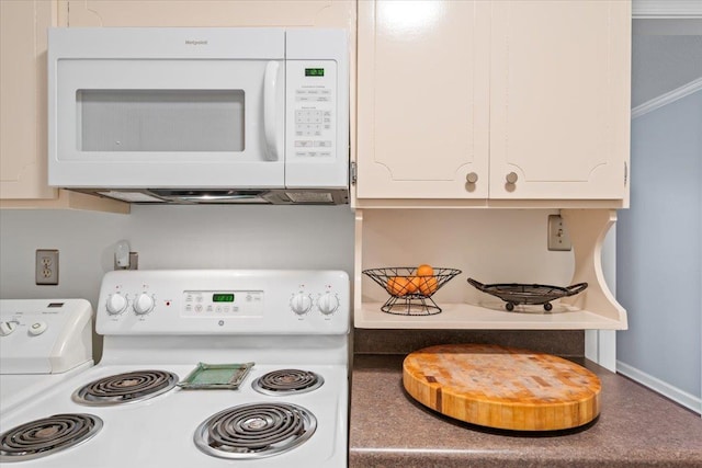 interior details with baseboards, white appliances, and white cabinets