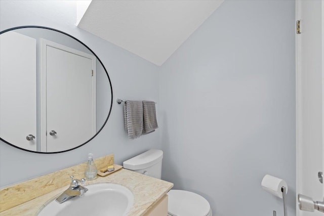 bathroom featuring toilet, vanity, and lofted ceiling