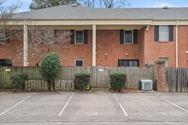 exterior space featuring uncovered parking, a fenced front yard, and central AC unit