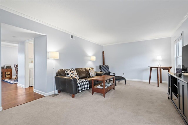 living area featuring light carpet, baseboards, visible vents, washer / clothes dryer, and crown molding