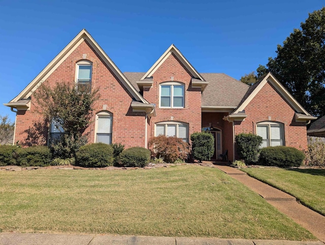 traditional home featuring brick siding, a front lawn, and roof with shingles