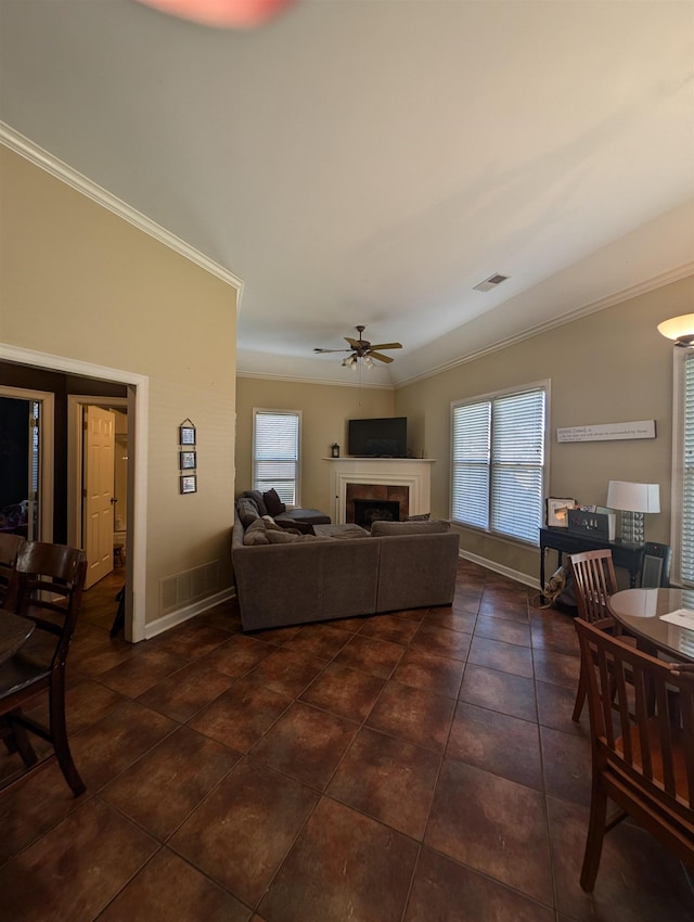 living area with crown molding, visible vents, a fireplace, and ceiling fan