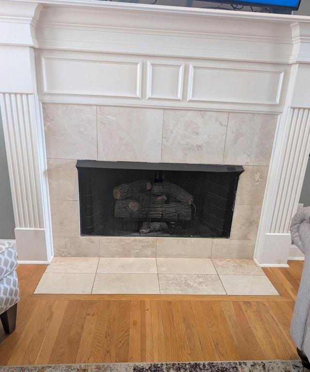 interior details with a tiled fireplace and wood finished floors