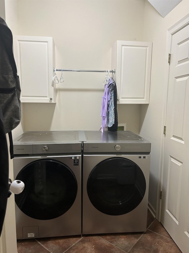 laundry room featuring dark tile patterned flooring, cabinet space, and washer and clothes dryer