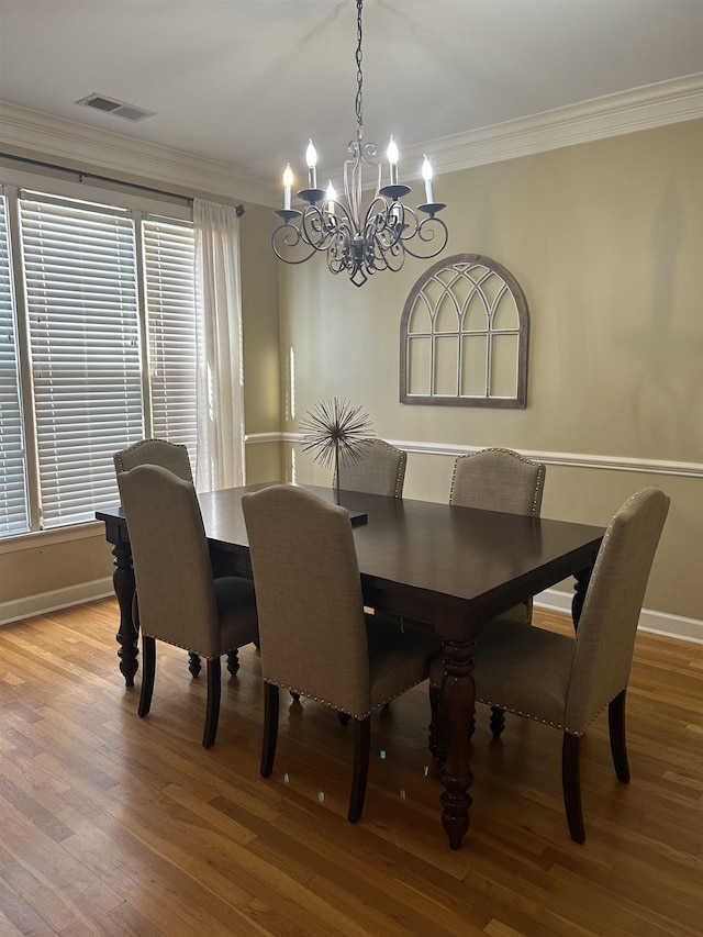 dining room with baseboards, crown molding, visible vents, and wood finished floors