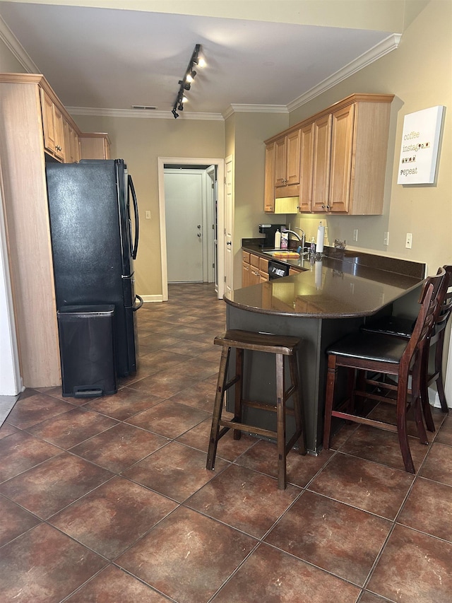 kitchen with dark countertops, ornamental molding, a breakfast bar, freestanding refrigerator, and light brown cabinetry