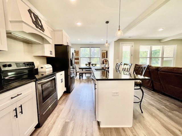 kitchen with stainless steel electric range oven, light wood finished floors, a breakfast bar area, and premium range hood