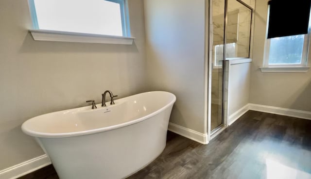 bathroom with a soaking tub, plenty of natural light, a shower stall, and wood finished floors