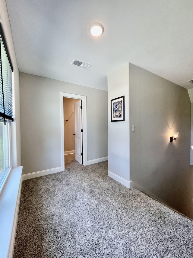 carpeted empty room with visible vents and baseboards