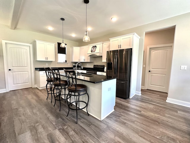 kitchen with appliances with stainless steel finishes, dark countertops, a sink, and white cabinets