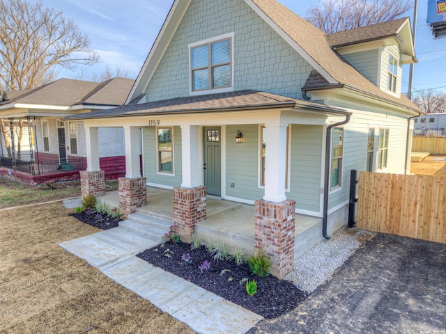 view of front of house with a shingled roof, fence, and a porch