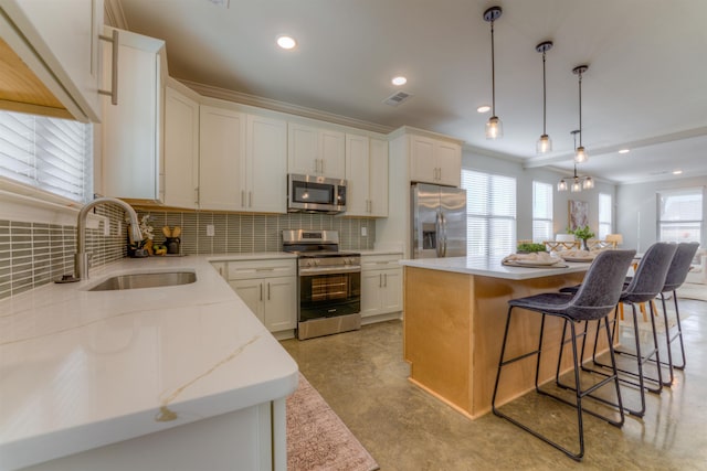 kitchen featuring a kitchen island, a sink, a kitchen breakfast bar, appliances with stainless steel finishes, and decorative backsplash