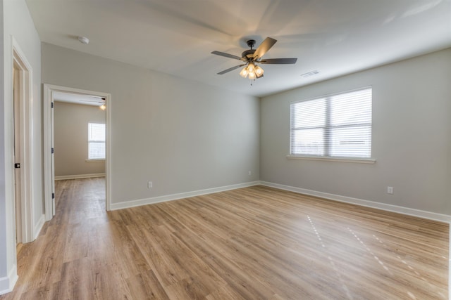 spare room with baseboards, visible vents, ceiling fan, and light wood finished floors