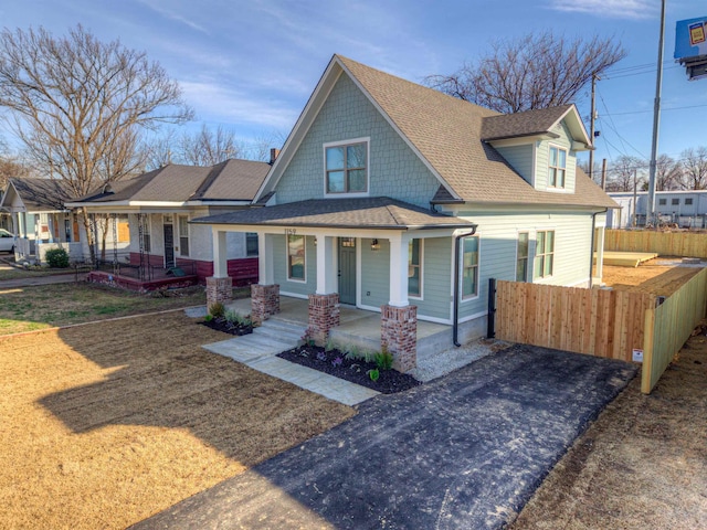 view of front of property featuring a porch, roof with shingles, and fence