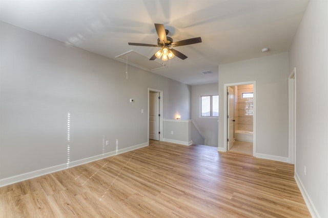 empty room featuring attic access, visible vents, light wood-style flooring, and baseboards