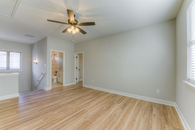 empty room featuring light wood-style floors, attic access, visible vents, and baseboards