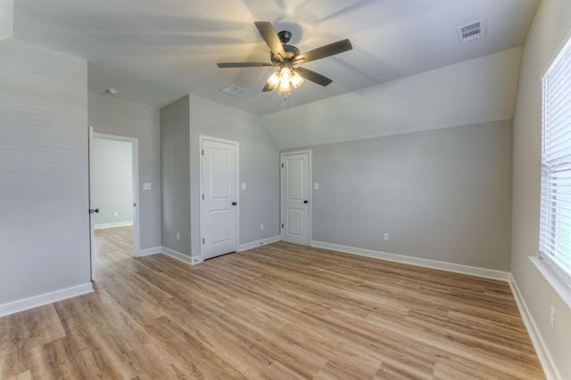 empty room featuring visible vents, baseboards, a ceiling fan, lofted ceiling, and light wood-style flooring