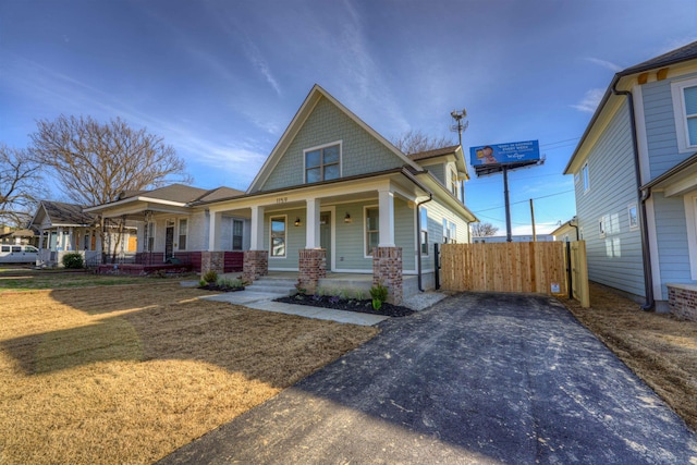 view of front of home featuring covered porch, fence, and a front lawn