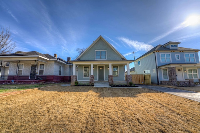 view of front of home with a porch, a front yard, and fence