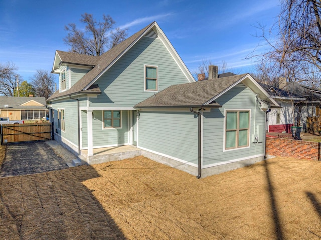 rear view of house featuring a shingled roof and fence