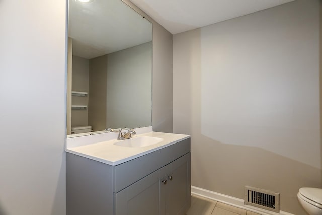 half bath featuring toilet, baseboards, visible vents, and vanity