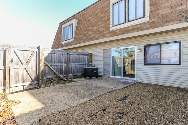 rear view of house featuring a shingled roof, a gate, a patio area, central AC, and fence