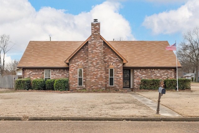 view of front of property with a shingled roof, brick siding, and a chimney