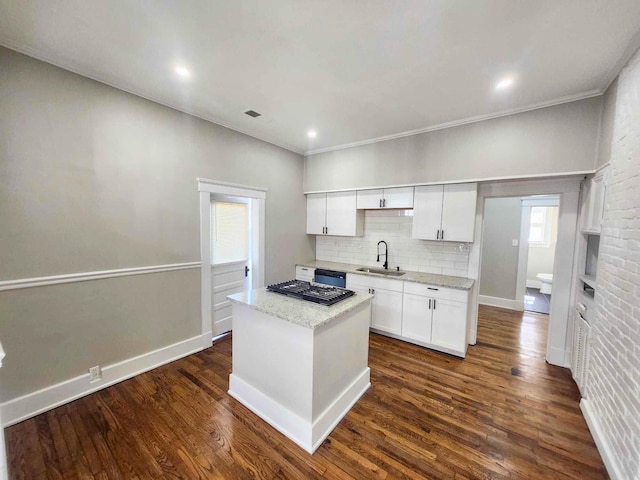 kitchen with tasteful backsplash, dark wood finished floors, white cabinets, and a sink