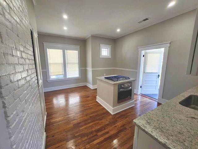 kitchen with light stone counters, dark wood-style floors, visible vents, appliances with stainless steel finishes, and ornamental molding