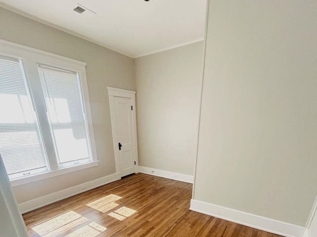 unfurnished room featuring visible vents, baseboards, and wood finished floors