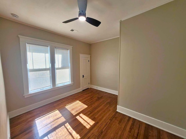 spare room featuring a ceiling fan, visible vents, baseboards, and dark wood-style flooring