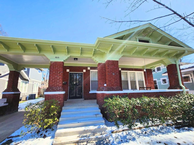 view of front of home featuring brick siding and a porch