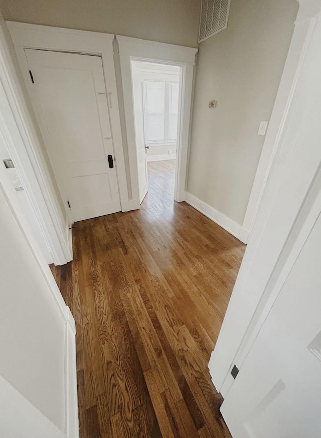 corridor with baseboards, visible vents, and wood finished floors