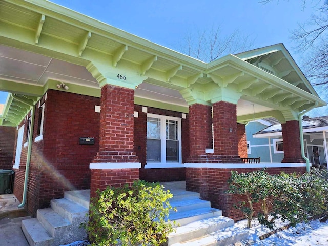 property entrance with covered porch and brick siding