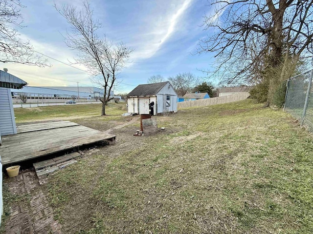 view of yard with a shed, a deck, a fenced backyard, and an outdoor structure